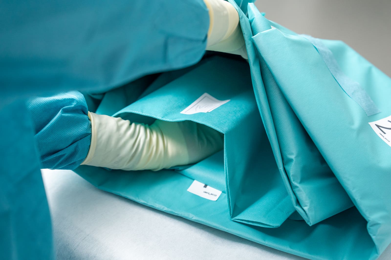 Gloved hands adjusting a sterile surgical drape